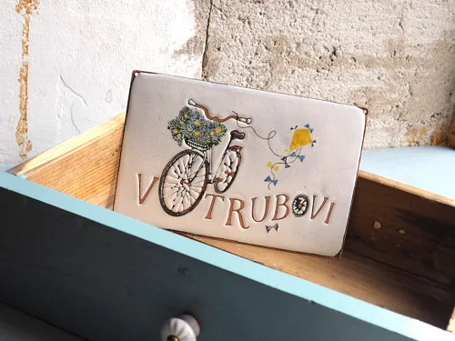 Vollständiges Schild mit Radsportmotiv, in einer blauen Holzschublade liegend.